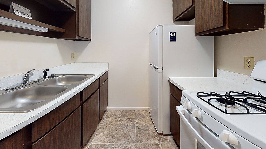 a gallery-style kitchen with a stove and a refrigerator a gallery-style kitchen with a stove and a refrigerator at Newport Village Apartments, Portage