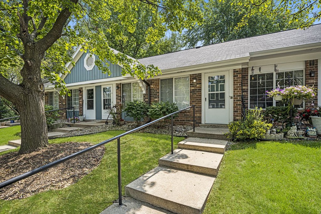 a house with stairs and a tree in front of it at Newport Village Apartments, Portage, MI