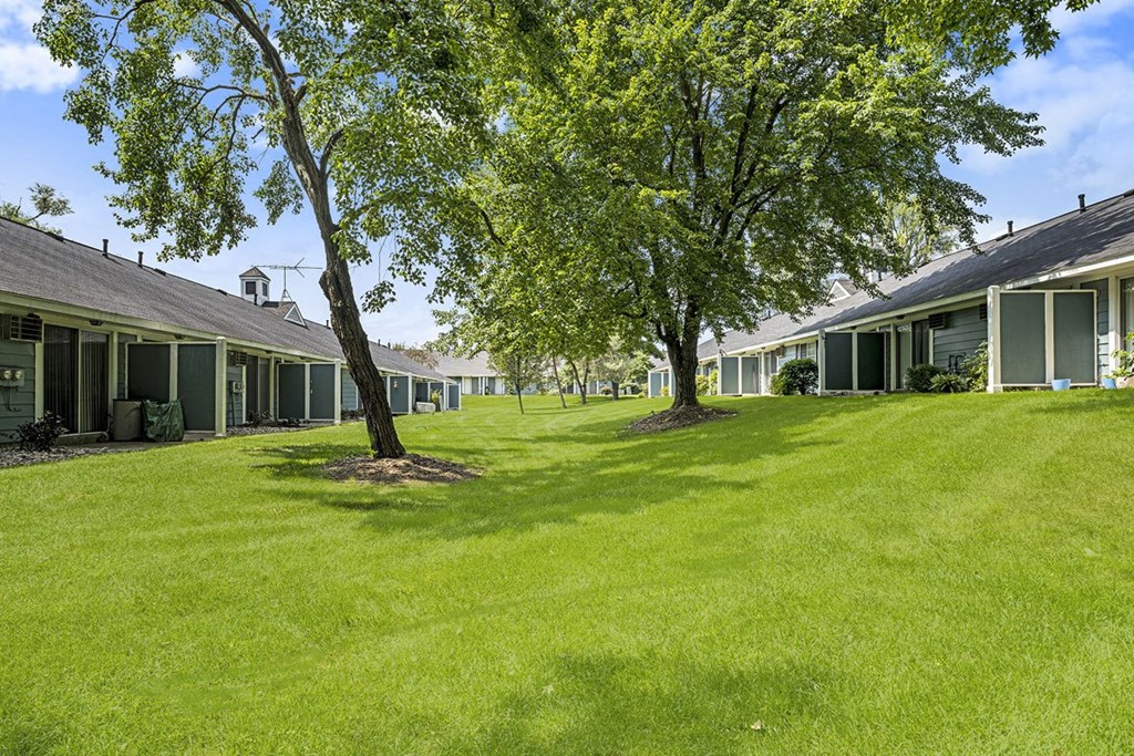 a green yard with mature shade trees at Newport Village Apartments, Portage, MI