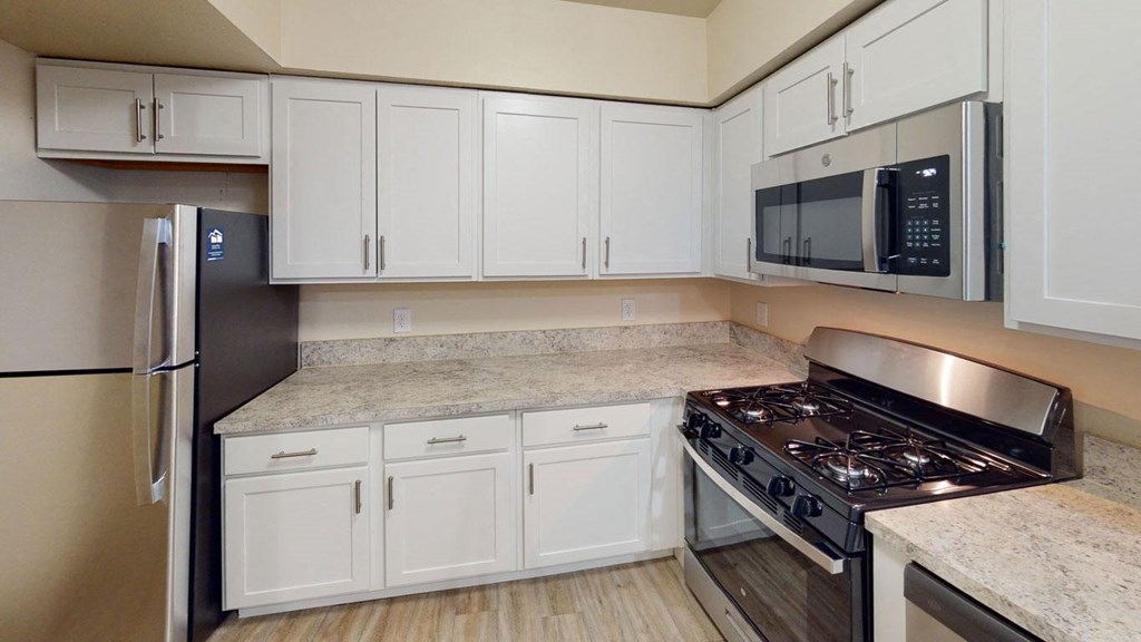 Renovated kitchen with white cabinets and a stove and a microwave at North Pointe Apartments in Elkhart, IN
