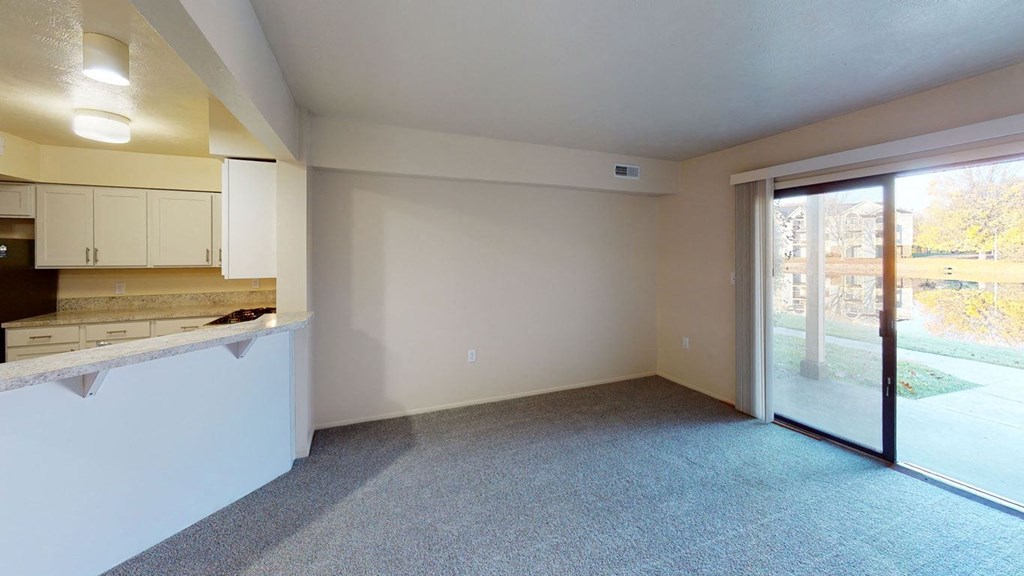 a living room with a kitchen and a sliding glass door at North Pointe Apartments in Elkhart, IN