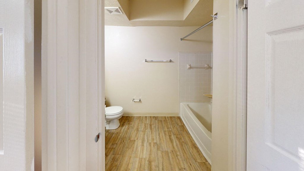 a renovated white bathroom with a toilet and a tub at North Pointe Apartments in Elkhart, IN