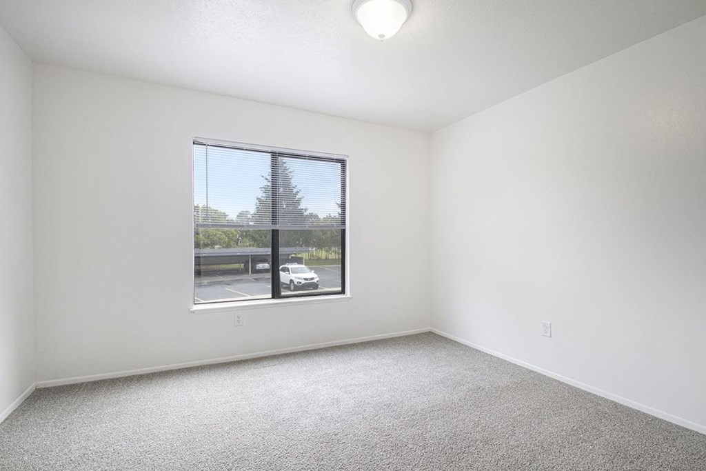 an spacious bedroom with a large window and carpeting at North Pointe Apartments in Elkhart, IN