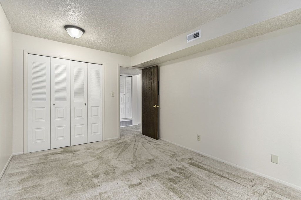 A bedroom with ample closet space and plush carpeting at Normandy Village Apartments in Michigan City, IN