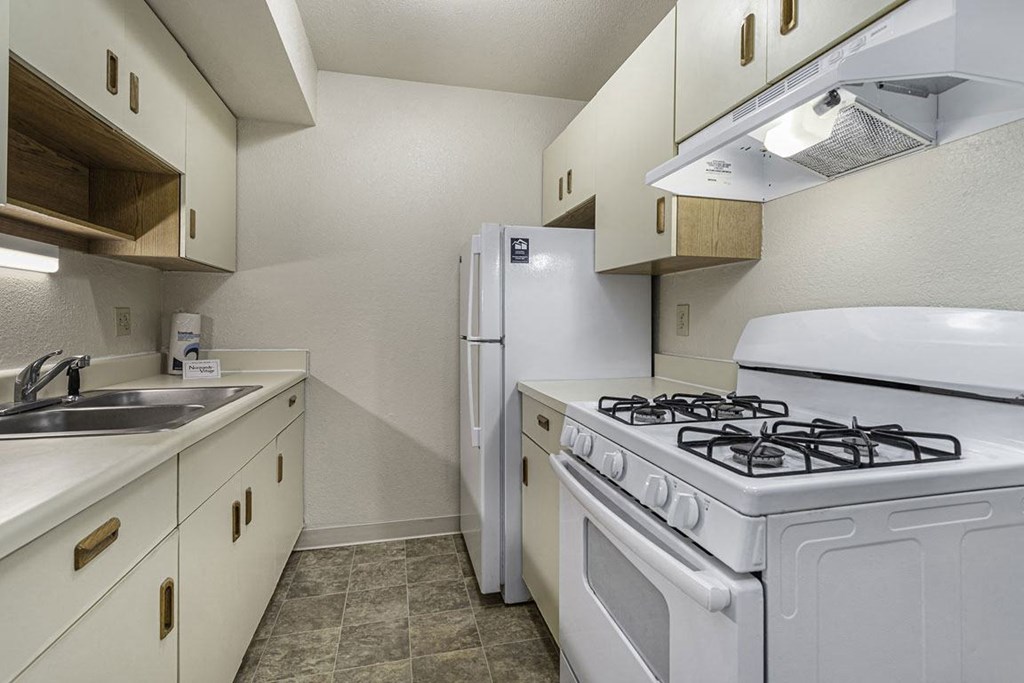 Galley kitchen with a stove and refrigerator and a sink at Normandy Village Apartments, Indiana, 46360