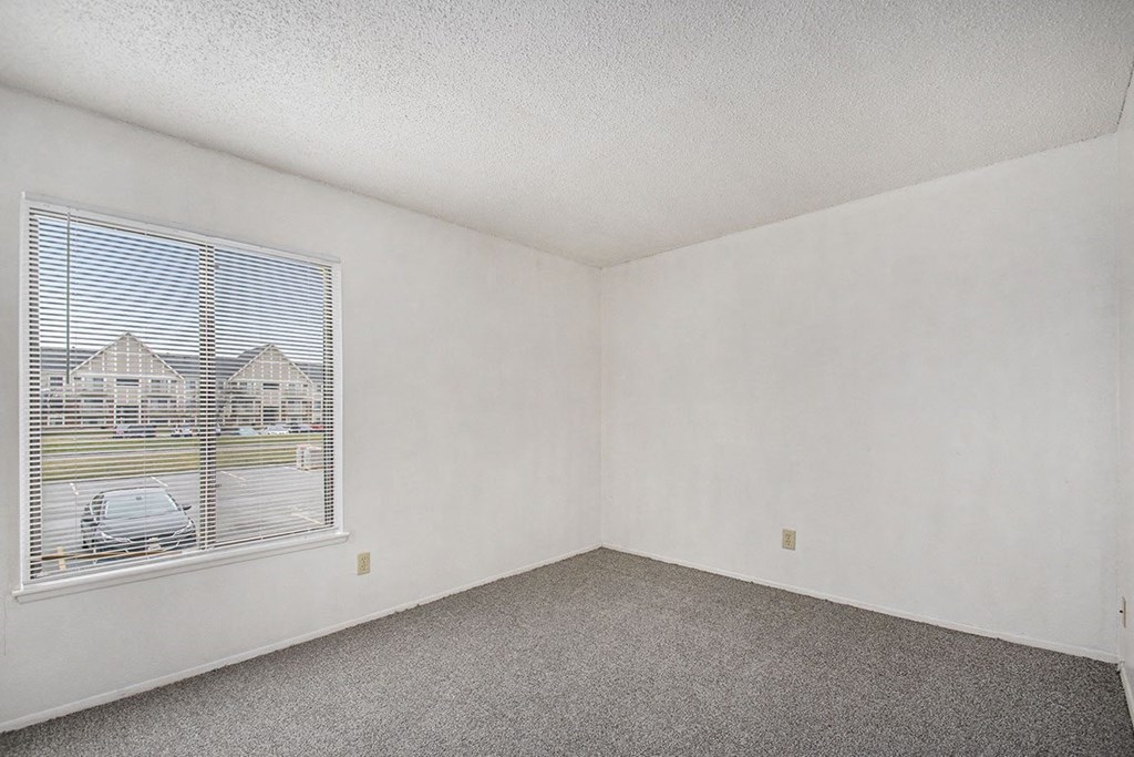 an empty bedroom with a large window and carpeting at Normandy Village Apartments, Michigan City, IN