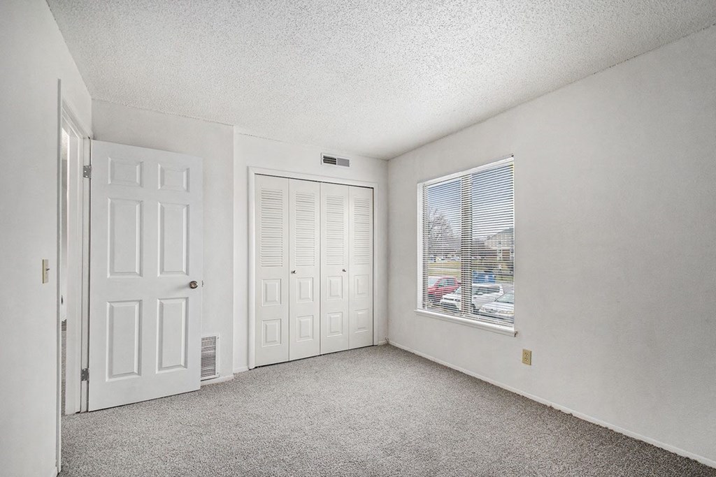 an empty bedroom with a window and a closet at Normandy Village Apartments, Indiana, 46360