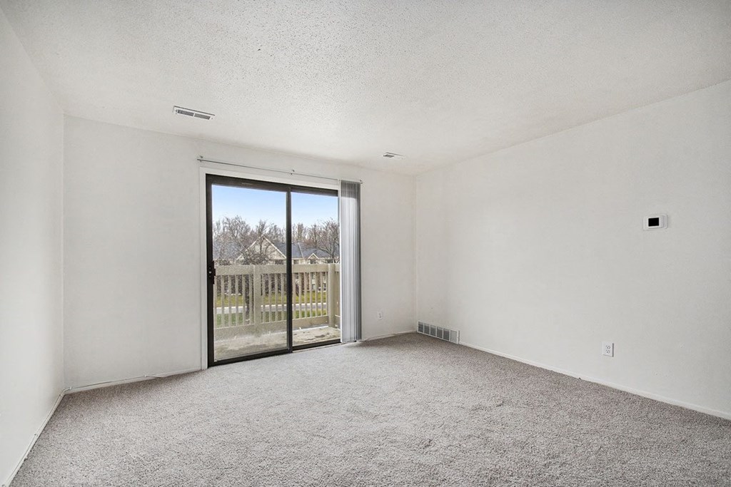 an empty living room with a sliding glass door to a balcony at Normandy Village Apartments, Michigan City, Indiana