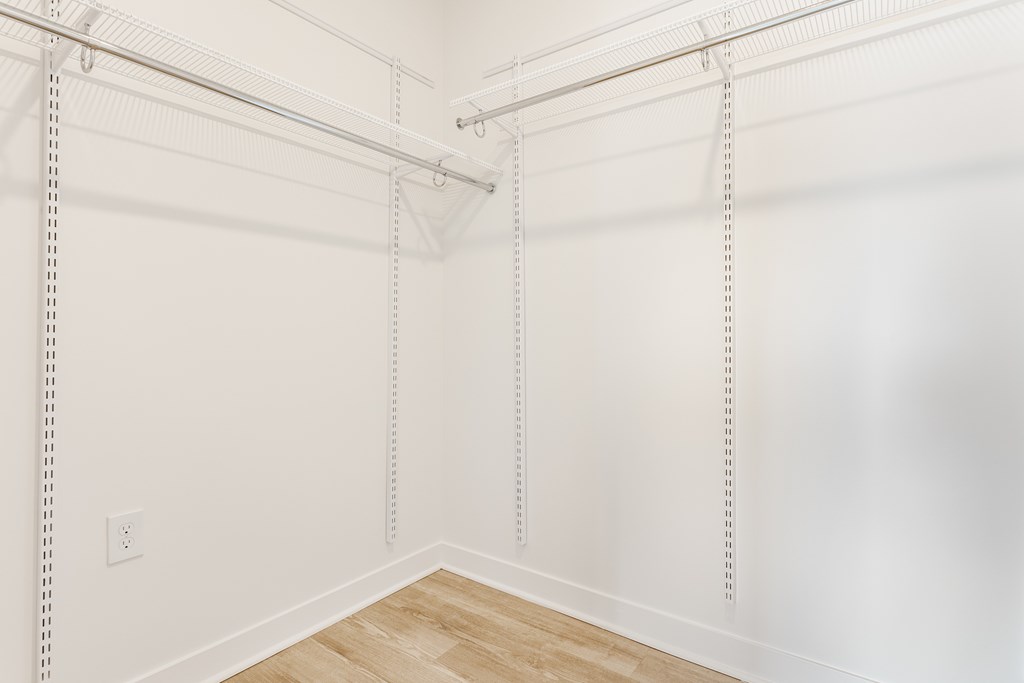 A white wall with a wooden floor and a white ceiling with a white pipe