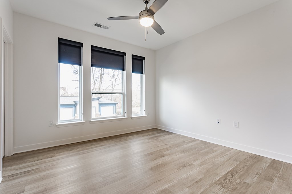 A room with a ceiling fan and three windows