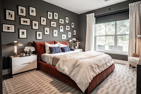 A bedroom with a large bed and a wall of picture frames.