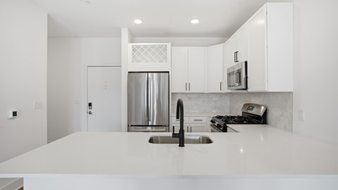 A modern kitchen with white cabinets and appliances.