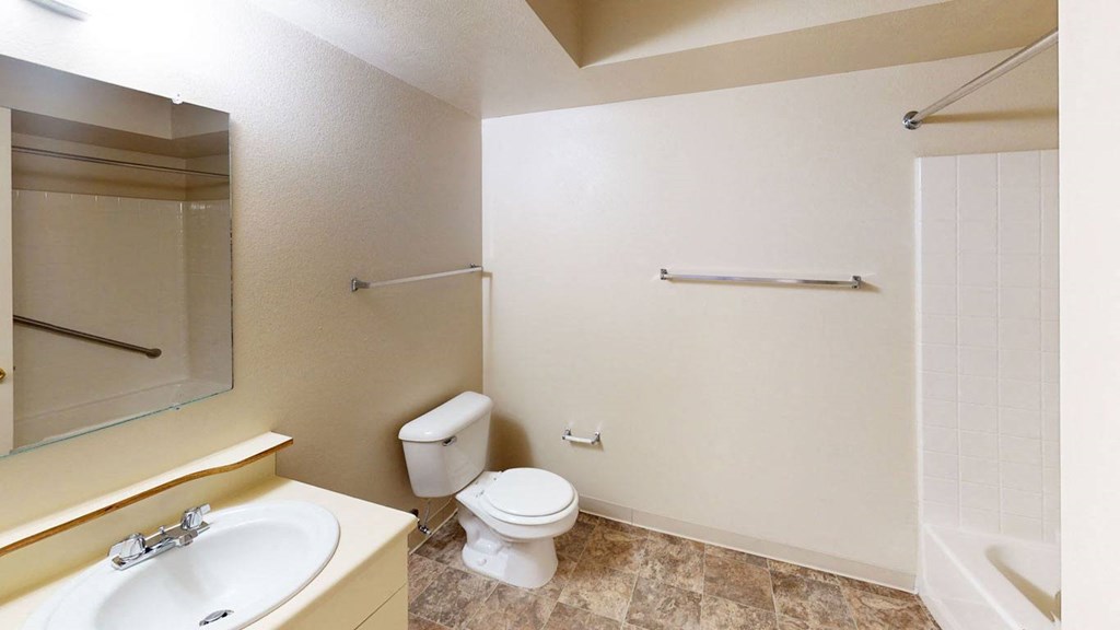 main bathroom with a toilet and a sink and a mirror at Orchard Lakes Apartments in Toledo, Ohio