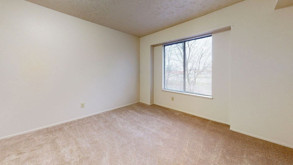 a bedroom with a large window and carpeting at Pine Knoll Apartments, Battle Creek, 49014