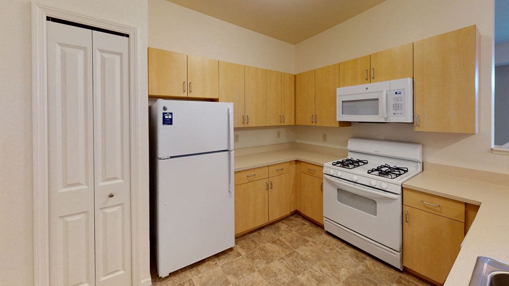 a kitchen with white appliances and wooden cabinets at Hunters Pond Apartment Homes in Champaign, IL