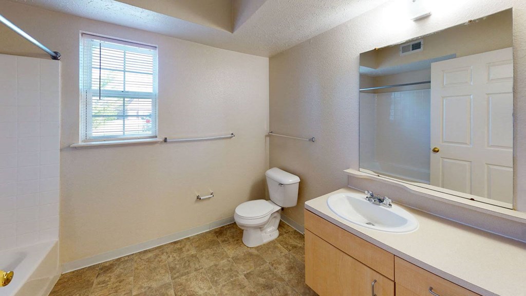a bathroom with a window, toilet and a sink and a mirror  at Hunters Pond Apartment Homes, Illinois, 61820