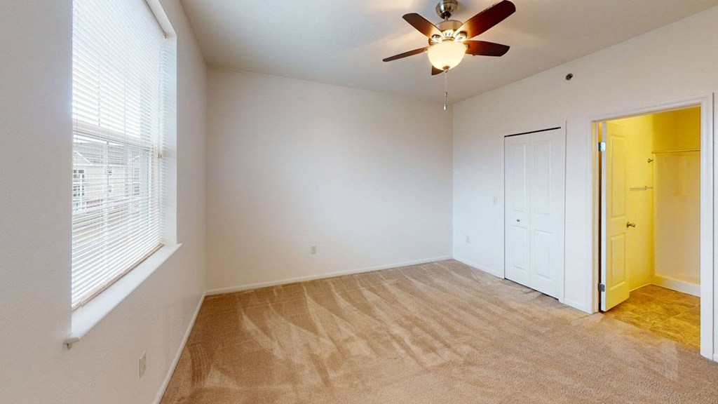 an empty living room with a ceiling fan and a door to a closet  at Hunters Pond Apartment Homes, Champaign