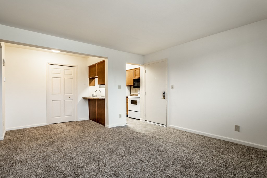 an empty living room and kitchen with white walls and carpet at Pheasant Run Apartments, Lafayette