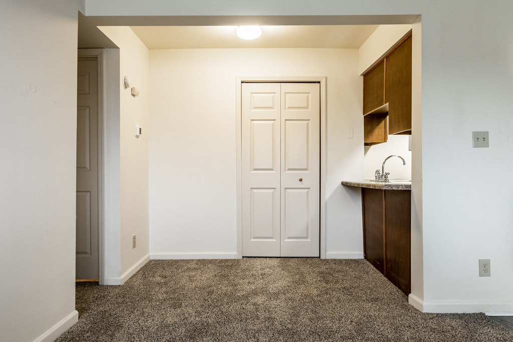an empty room with a door and a kitchen at Pheasant Run Apartments, Lafayette, Indiana