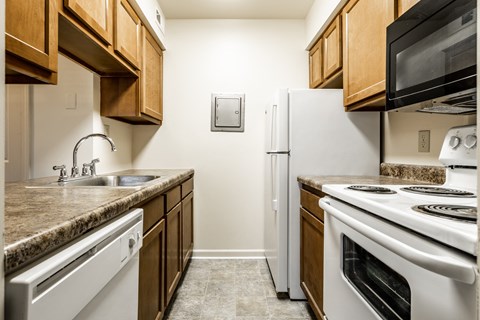 a kitchen with white appliances and wooden cabinets and a counter top