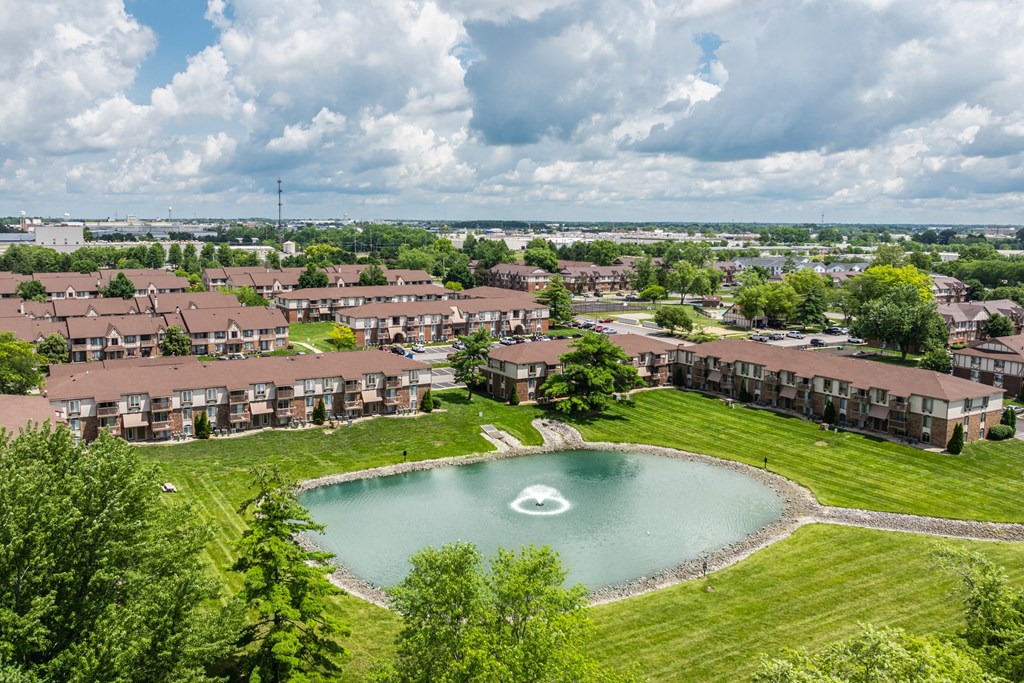 A large pond in the middle of a grassy area surrounded by houses