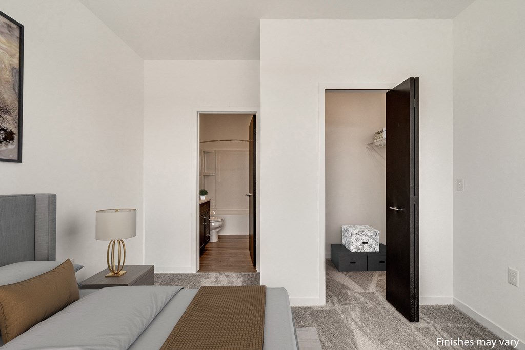 a bedroom with a bed and a door that leads to a bathroom  at Uptown Square Apartments, Michigan