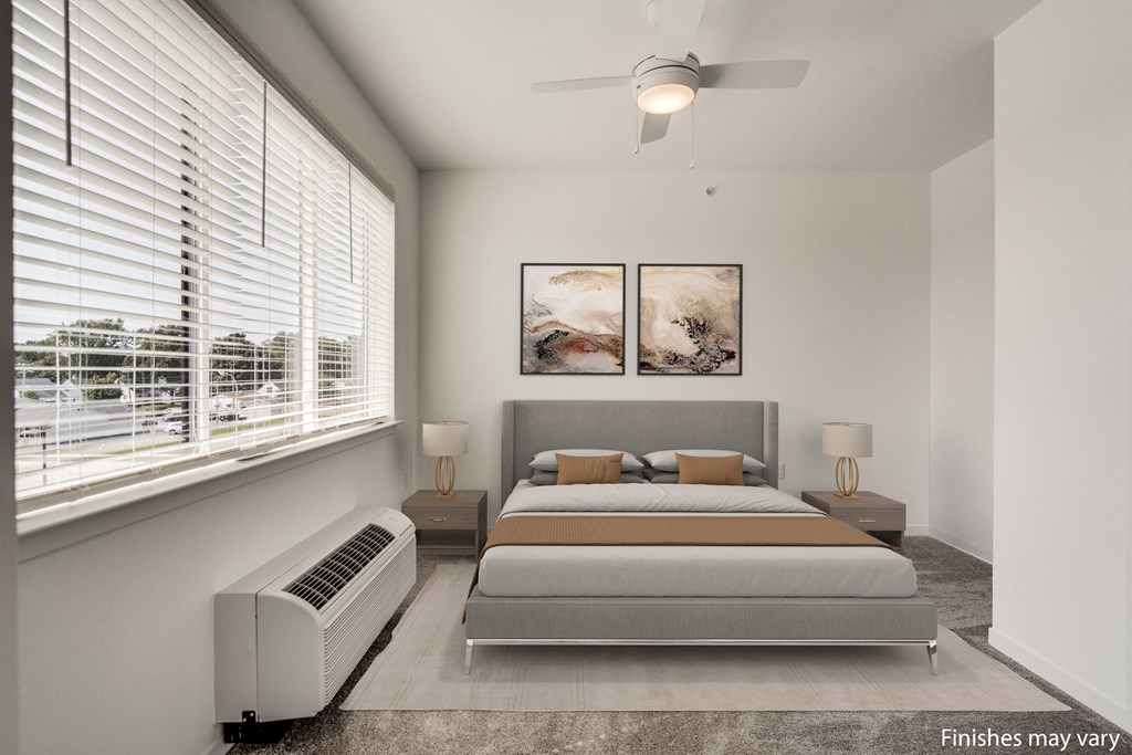 a bedroom with a bed and two windows  at Uptown Square Apartments, Troy, 48083