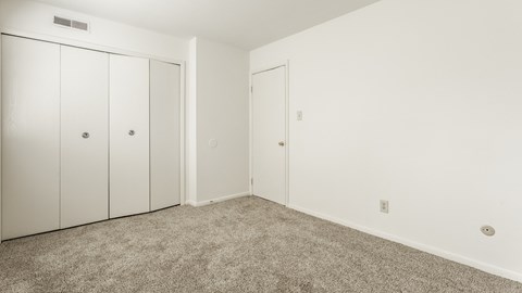 a bedroom with carpet and white walls and doors at Polo Run Apartments, Greenwood