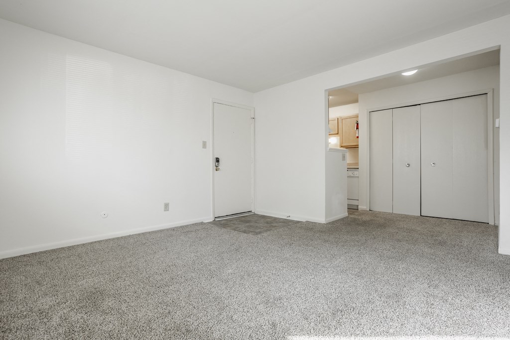 a living room with white walls and carpet and a door to a kitchen at Polo Run Apartments, Indiana, 46142