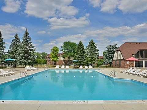 Outdoor swimming pool with lounge chairs and umbrellas 2 at Charter Oaks Apartments, Davison, Michigan