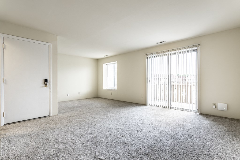 an empty living room with a door to a balcony at Scarborough Lake Apartments, Indiana, 46254