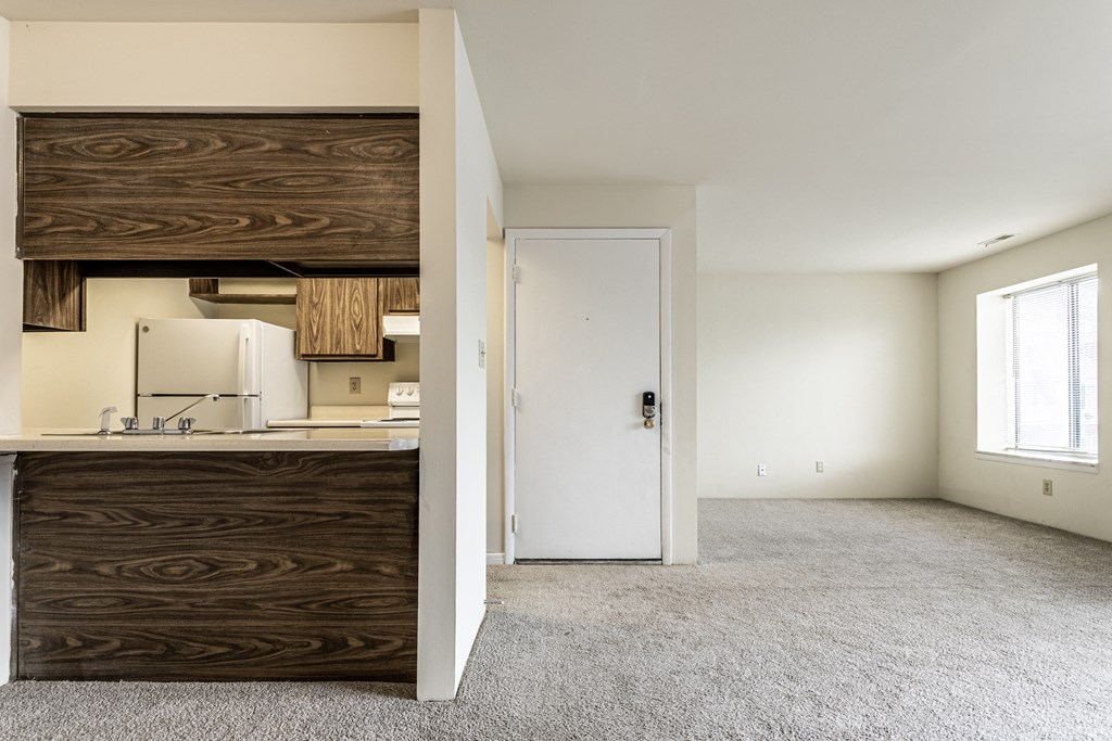 an empty living room with a kitchen and a door to a white room at Scarborough Lake Apartments, Indianapolis, 46254