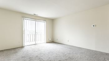 an empty living room with white walls and a sliding glass door in Indianapolis, IN