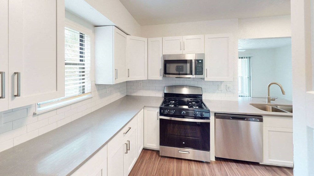 a kitchen with white cabinets and a stove and a microwave at Green Ridge Apartments, Michigan, 49544