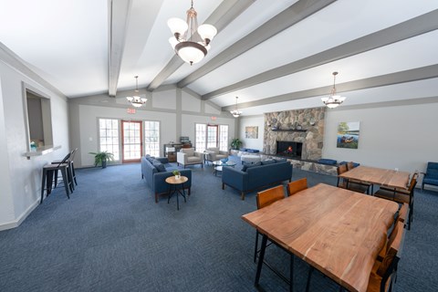 A spacious room with a fireplace and a dining table set up at Rivers Edge Apartments, Waterford, MI