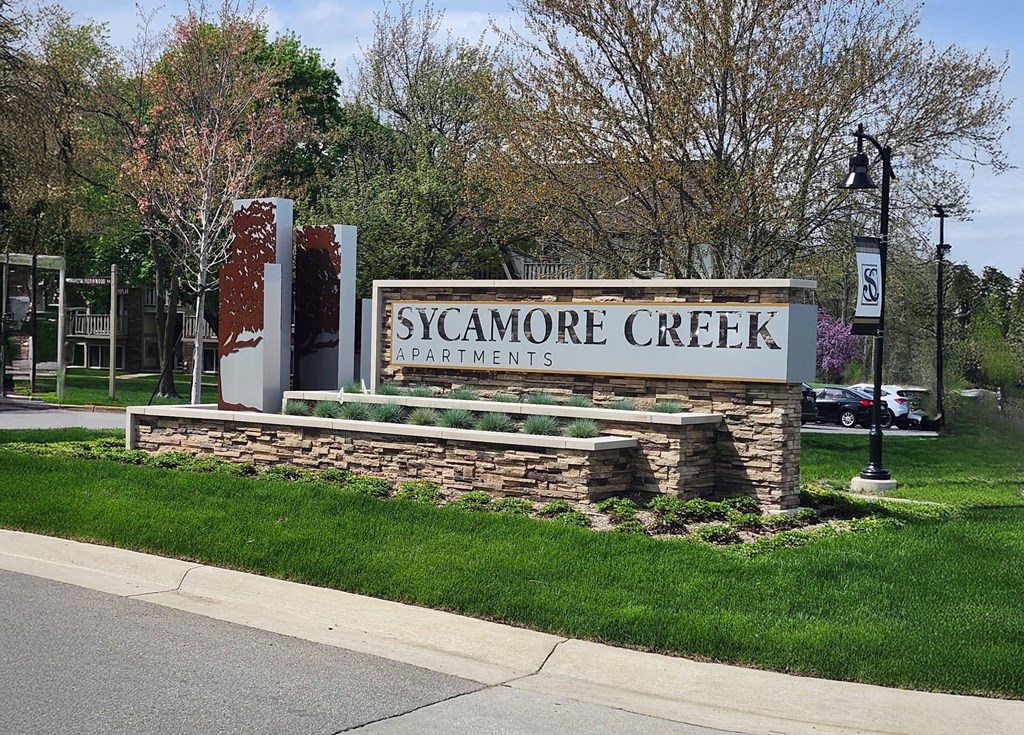 Property Signage for Sycamore Creek Apartments is displayed in front of a grassy area.