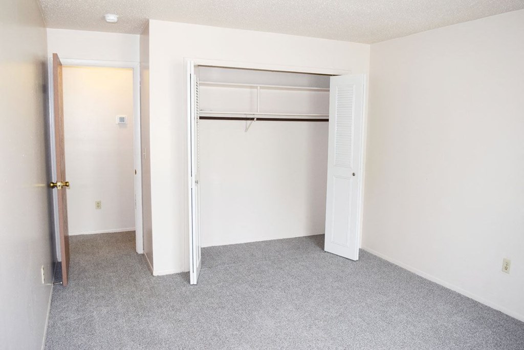 an empty bedroom with a closet and an open door at Seville Apartments in Kalamazoo, MI 49009