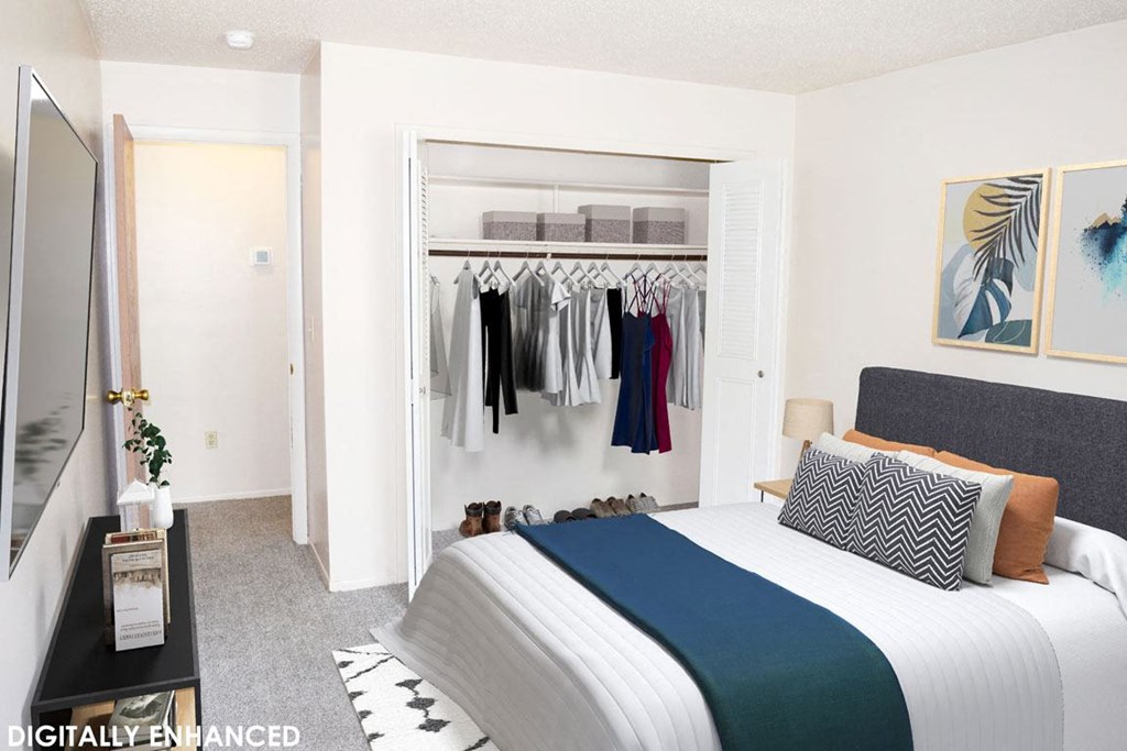 a bedroom with a bed and a closet full of clothes at Seville Apartments, Kalamazoo, MI, 49009