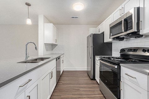 a kitchen with stainless steel appliances and white cabinets  at Signature Pointe Apartment Homes, Athens, Alabama