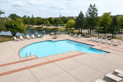 A large outdoor swimming pool surrounded by lounge chairs and trees.