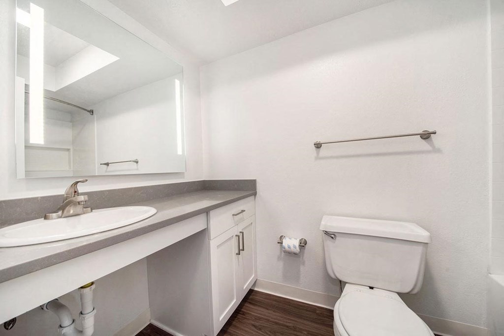 a bathroom with hard surface floors and a mirror at Stoney Pointe Apartment Homes, Wichita