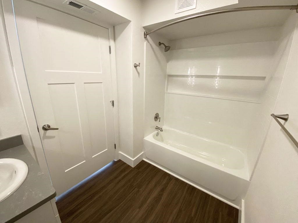 a bathroom with a tub and a sink and a door at Stoney Pointe Apartment Homes, Wichita