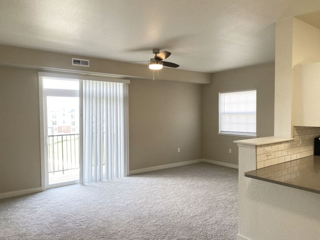enlarged living room with a ceiling fan and plush carpeting at Stoney Pointe Apartment Homes, Wichita, KS