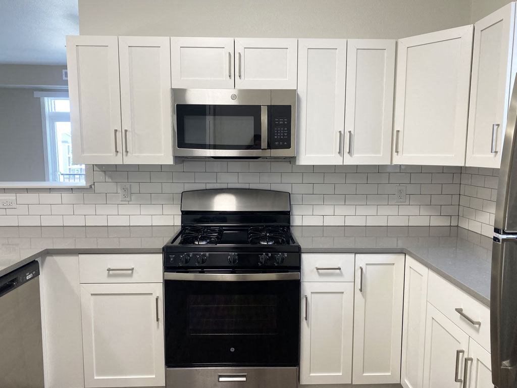 a kitchen with white cabinets and a stove and a microwave at Stoney Pointe Apartment Homes, Wichita, 67226
