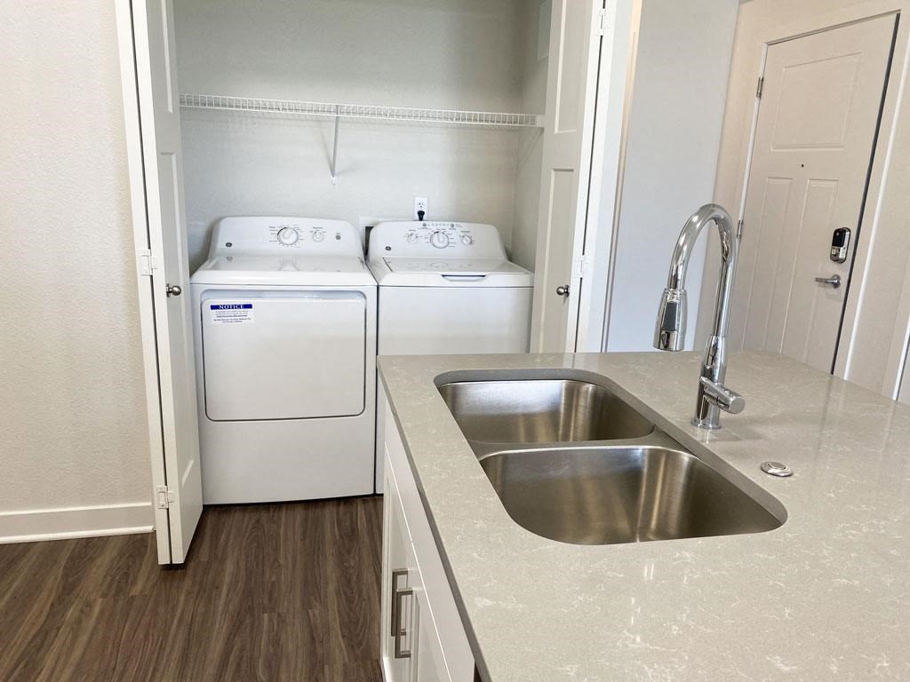 a kitchen with a sink and washer and dryer at Stoney Pointe Apartment Homes, Kansas