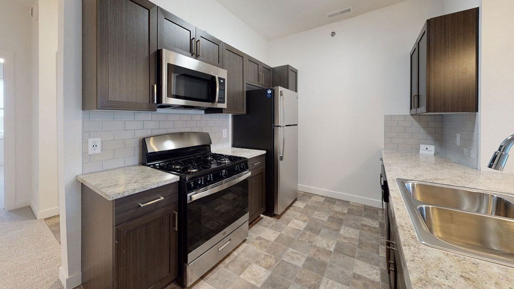 a kitchen with stainless steel appliances and wooden cabinets at Strathmore Apartment Homes, West Des Moines, 50266
