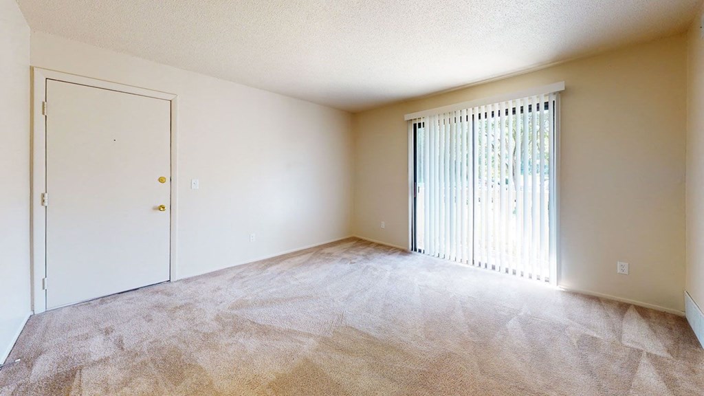 an empty living room with a sliding door to a patio at Swiss Valley Apartments, Wyoming, MI