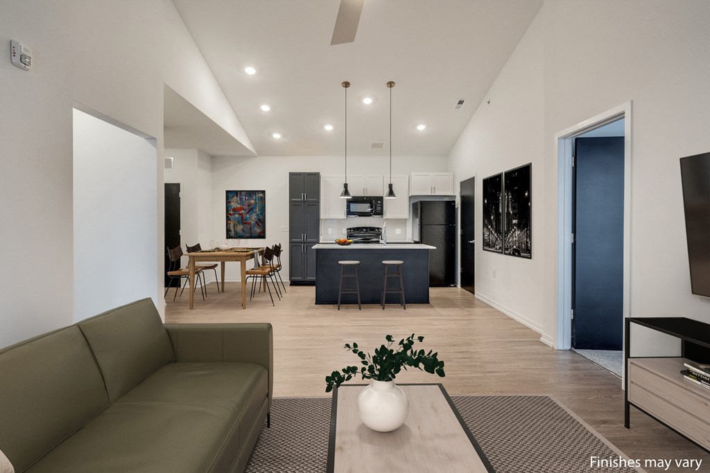 a living room with a couch and a table with chairs in front of a kitchen with a  at Uptown Square Apartments, Michigan, 48083