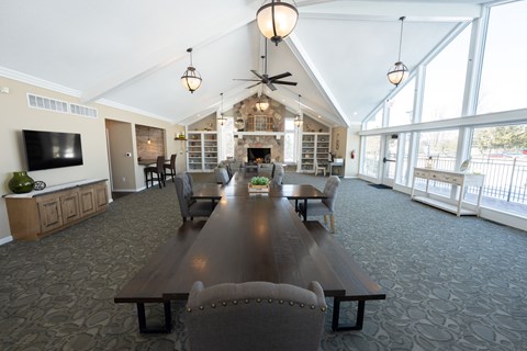 A large wooden table is surrounded by chairs in a spacious room with a fireplace.