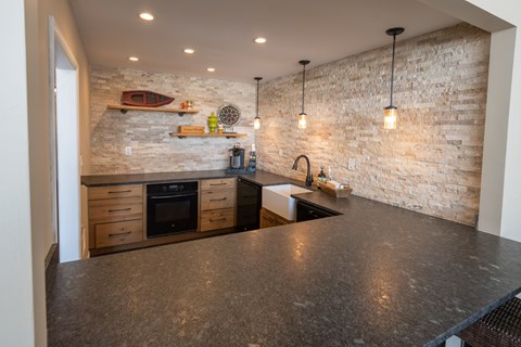 A kitchen with a stone wall and a black counter top.